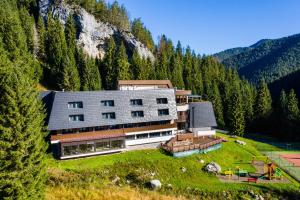 un grand bâtiment au sommet d'une colline plantée d'arbres dans l'établissement Wellness Hotel Repiska, à Demänovská Dolina