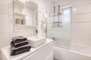 a white bathroom with a sink and a mirror at 75 m2 calme avec jacuzzi I Proche métro B - 9 min in Toulouse