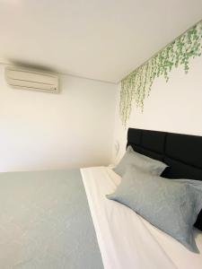a bedroom with a bed with a plant on the wall at Apartamento a 100 m da praia in Juquei