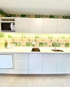 a kitchen with white cabinets and a tile wall at Apartamento a 100 m da praia in Juquei