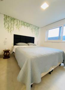 a white bedroom with a large bed and a window at Apartamento a 100 m da praia in Juquei