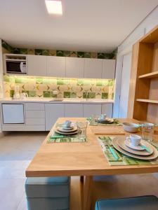 a kitchen with a wooden table with dishes on it at Apartamento a 100 m da praia in Juquei