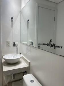 a bathroom with a sink and a toilet and a mirror at Apartamento a 100 m da praia in Juquei