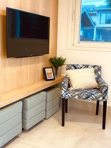 a living room with a tv on a wall with a chair at Apartamento a 100 m da praia in Juquei