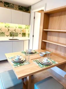 a kitchen with a wooden table with plates and cups at Apartamento a 100 m da praia in Juquei
