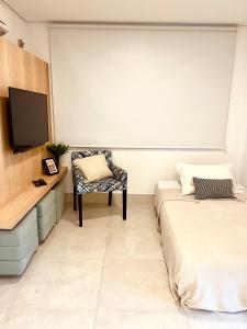a room with two beds and a tv and a chair at Apartamento a 100 m da praia in Juquei