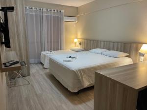a hotel room with two beds and a table at Aquarius Flat Aptos e Suítes in Santa Cruz do Sul