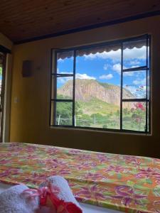 a bedroom with a bed with a view of a mountain at Pousada Fulô da Pedra in Serra de São Bento