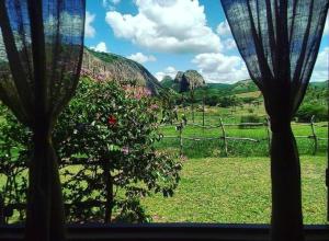 a view of a field from a window with curtains at Pousada Fulô da Pedra in Serra de São Bento