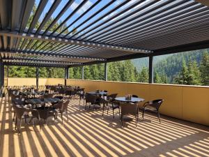 a restaurant with tables and chairs on a deck at Wellness Hotel Repiska in Demanovska Dolina