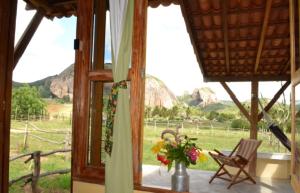 a window with a chair and a vase of flowers at Pousada Fulô da Pedra in Serra de São Bento