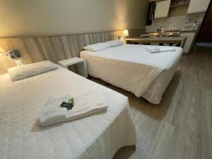 two beds in a hotel room with towels on them at Aquarius Flat Aptos e Suítes in Santa Cruz do Sul