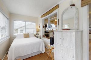 a white bedroom with a bed and a mirror at Linda's Cozy Cottage "C" in Laguna Beach