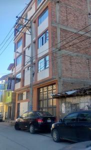 two cars parked in front of a brick building at Chacraraju Hostel in Huaraz