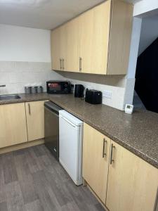 a small kitchen with wooden cabinets and a dishwasher at Northampton town in Kingsthorpe