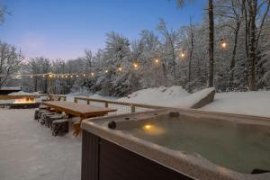 a hot tub in the snow next to a picnic table at Maple Pine w Hot Tub Pool Table 3min to Mount Snow in Dover