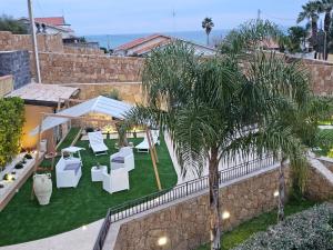 d'un jardin avec un mobilier blanc et un palmier. dans l'établissement Casa Maya, à Brucoli