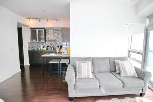 a living room with a couch and a kitchen at Presidential 2+1BR Condo, Entertainment District (Downtown) w/ CN Tower View, Balcony, Pool & Hot Tub in Toronto