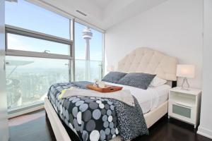 a bedroom with a bed and a large window at Presidential 2+1BR Condo, Entertainment District (Downtown) w/ CN Tower View, Balcony, Pool & Hot Tub in Toronto