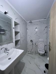 a white bathroom with a sink and a toilet at Eveline Boutique Apartments in Sarandë