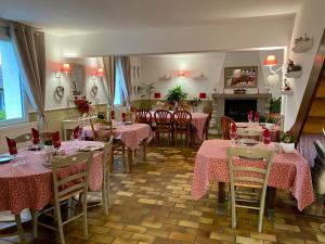 a dining room with pink tables and chairs and a fireplace at La Besace in Sainte-Croix