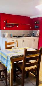cocina con mesa y cocina con paredes rojas en Le Montadou, en Coucouron
