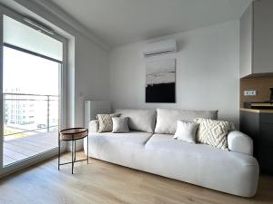 a living room with a white couch and a large window at Apartament Lina Koralowa in Lublin