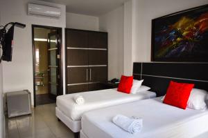 2 letti in camera con cuscini rossi di Hotel Or Cartagena a Cartagena de Indias