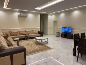 شقه غرفتين نوم وصاله ومجلس ومطبخ في الرياض: غرفة معيشة مع أريكة وتلفزيون بشاشة مسطحة