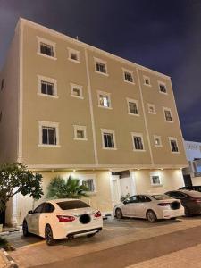 شقه غرفتين نوم وصاله ومجلس ومطبخ في الرياض: سيارتين متوقفتين أمام مبنى كبير