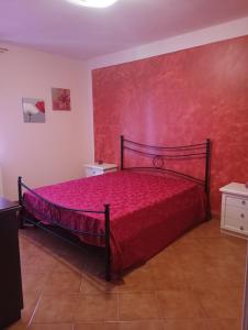 a bedroom with a bed with a red wall at podere il poggetto in Lorenzana