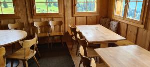 een kamer met houten tafels, stoelen en ramen bij Skihaus Hochwang in Arosa