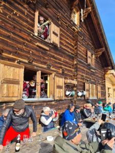 un groupe de personnes assises à des tables devant un bâtiment dans l'établissement Skihaus Hochwang, à Arosa