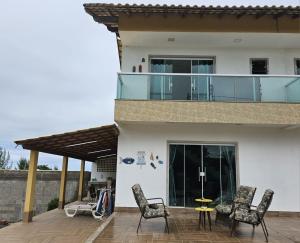 a house with a balcony and chairs on a patio at Casa de Praia frente pro Mar Marataízes in Saco dos Cações