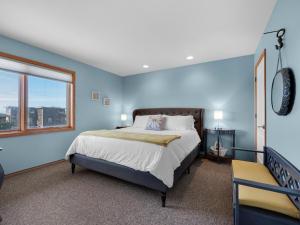 a blue bedroom with a bed and a window at Shoreline Solace: Ocean View Townhouse Tillamook in Tillamook