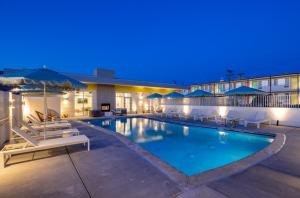 a hotel pool with chairs and umbrellas at night at The Imperial in Albuquerque