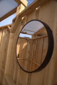 einen Spiegel an einer Holzwand mit einem Holzzaun in der Unterkunft Trevena Cross Bell Tent in Helston