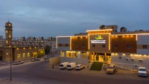 a large building with cars parked in a parking lot at Al Nakheel Park Serviced Apartment in Riyadh