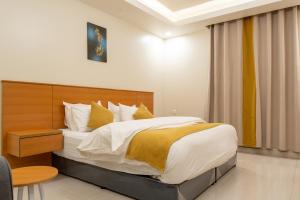 a bedroom with a large bed with white and yellow pillows at Al Nakheel Park Serviced Apartment in Riyadh