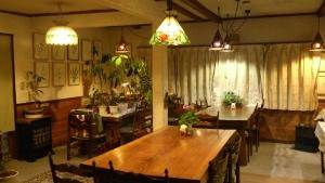 una sala da pranzo con tavoli, sedie e luci a ciondolo di Gallery & Lodge Noichigo a Hakuba