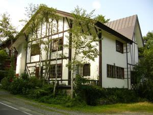a white house with black windows on a street at Gallery & Lodge Noichigo in Hakuba