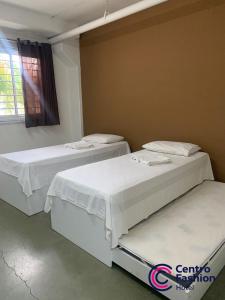two beds in a room with a window at Hotel Centro Fashion in Fortaleza