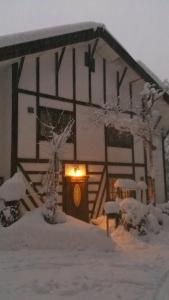 a cabin in the snow with a light on the door at Gallery & Lodge Noichigo in Hakuba