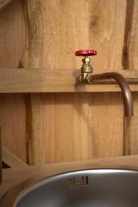 eine Küchenspüle mit einem Wasserhahn an einer Holzwand in der Unterkunft Trevena Cross Bell Tent in Helston