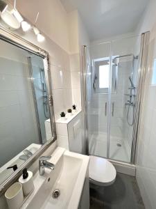 a white bathroom with a shower and a sink at Apartmani Jarun in Zagreb
