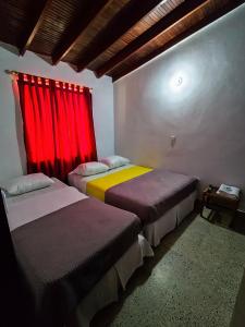 2 letti in una camera con tenda rossa di Construyendo Sueños JL a Medellín