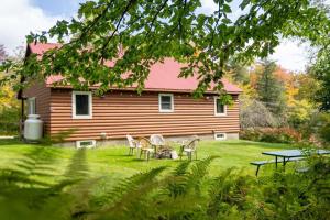 a house with chairs and a table in the yard at Cozy Cabin in Stratton Mountain & Mount Snow 10min in Stratton