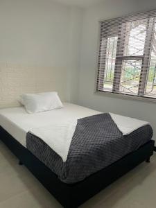 Bett in einem weißen Zimmer mit Fenster in der Unterkunft Hotel Portobello La Ceja in La Ceja
