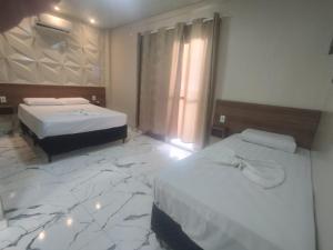 um quarto de hotel com duas camas e um piso de mármore em Hotel Rio Claro em Rio Claro