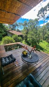 ein Tisch und ein Stuhl auf einem Holzdeck in der Unterkunft Villa Gatto Chalés - Visconde de Maua in Bocaina de Minas + 108 Fotos